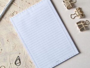 Zu sehen ist ein Notizblock mit einem grauen Tulpenmuster. Das Muster umrahmt die Schreiblinien.